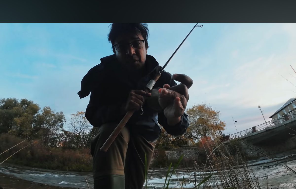 Angler on the bank of the Ganaraska River in Port Hope holding a float rod at dusk